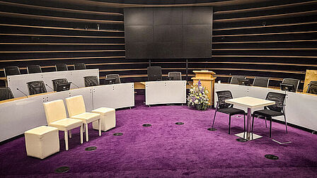 Ronde zaal met paarse vloerbedekking met tafeltje en stoelen