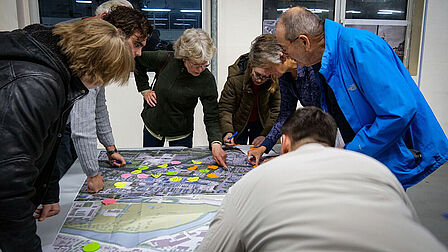 Mensen staan gebogen over een kaart met post-its erop geplakt