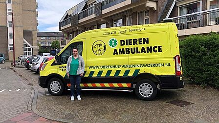 Vrouw staat voor busje van de dierenambulance