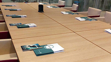Tafel met folders en pennen erop en lege stoelen eraan
