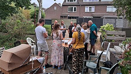 Groepje mensen staat om een tafel in een achtertuin