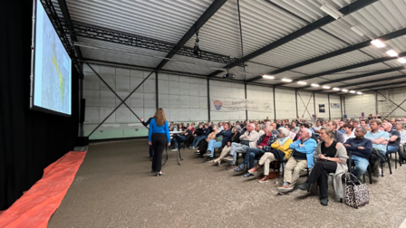 Mensen zitten in een hal en luisteren naar een presentatie
