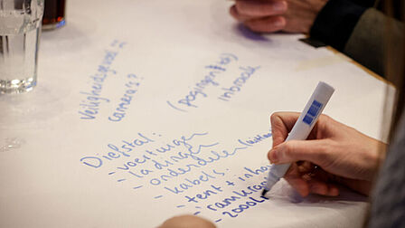 Persoon schrijft met stift op een vel papier