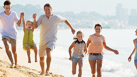 Een man, vrouw en drie kinderen rennen op een strand