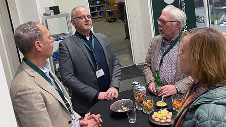 Vier mensen staan bij een tafel met versnaperingen