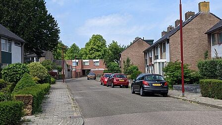 Straat met huizen en geparkeerde auto's