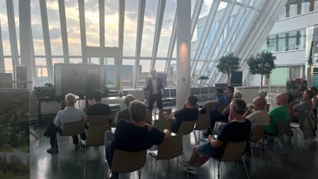 Mensen luisteren in het Stadshuis naar een presentatie