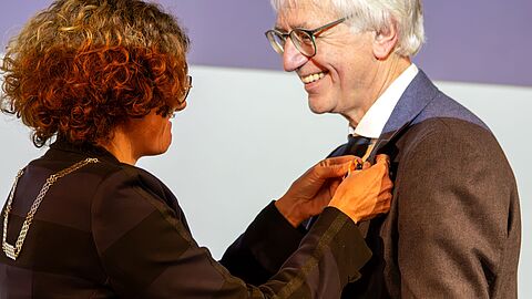 Burgemeester Marijke van Beukering speldt onderscheiding op de borst van Willem den Hartog