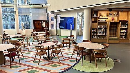 Ruimte met tafels, stoelen en een scherm
