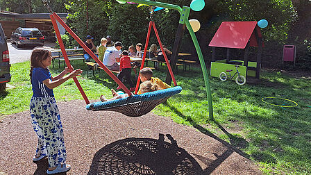 Kind bij schommel en mensen aan een picknickbank
