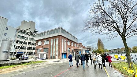 Groep mensen loopt op een fabrieksterrein