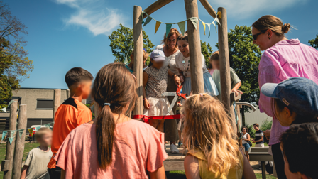 Wethouder Ellie Eggengoor in een speeltoestel met kinderen om haar heen