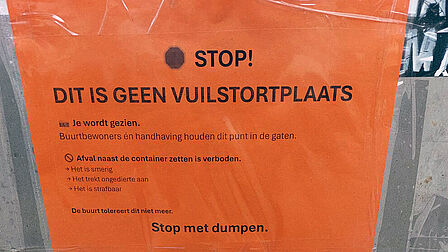 Poster met tekst: Stop! Dit is geen vuilstortplaats. Je wordt gezien. Buurtbewoners én handhaving houden dit punt in de gaten. Afval naast de container zetten is verboden. Het is smerig. Het trekt ongedierte aan. Het is strafbaar. De buurt tolereert dit niet meer. Stop met dumpen.