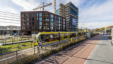 Tram met rechts een fietspad en links een hoog gebouw