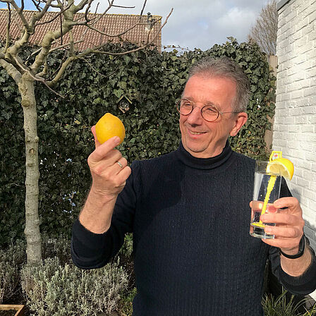 Man in de tuin met drankje en citroen in de hand
