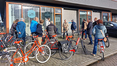 Groep mensen met fiets voor het gebouw van Cake Queen