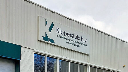 Bord aan een bedrijfspand met tekst: Kippersluis b.v. installatieburo voor elektrotechniek en beveiligingen