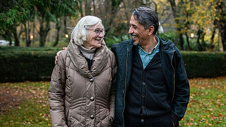 Een man en een vrouw staan naast elkaar en lachen naar elkaar