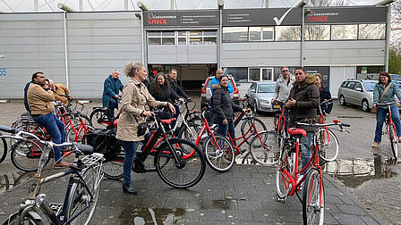 Groep mensen met fiets voor een garagebedrijf