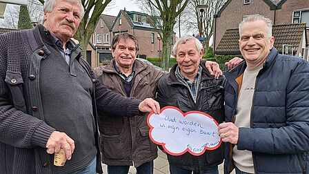 Vier mannen houden een papiertje omhoog waarop geschreven staat: Oud worden in mijn eigen buurt