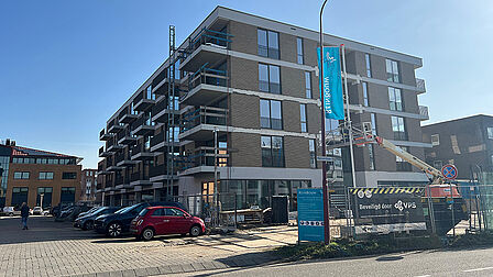 Nieuw appartementengebouw met geparkeerde auto's ernaast