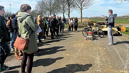 Man praat buiten met een microfoon tegen een groep mensen