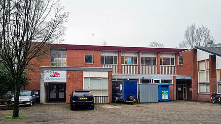 Schoolgebouw met geparkeerde auto ervoor