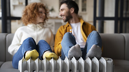 Vrouw en man op de bank met voeten op radiator